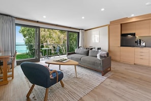 A spacious living room layout with large, glass balcony doors opening up to the coastal views
