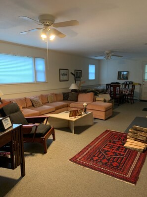 Family room with large sectional and table at end of room. Leads to screened por