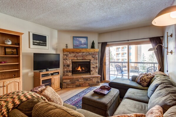 Living Room Area - The living room area has a comfortable sofa, cozy fireplace, and a TV. The living room opens up to a large balcony.