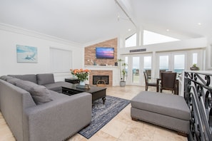 One of two living rooms in the rental, this second level living area includes a large sofa, cable TV, dining table for four, and French doors that lead to your beachfront patio.