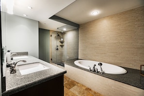 Gray granite bathtub surround and countertops with flagstone tiling surrounding the bath tub and shower