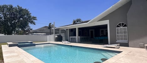 Heated pool with bar stools. Travertine pavers.