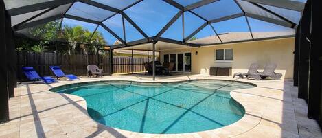 Tropical yard with screened, heated salt-water pool and patio for dining.