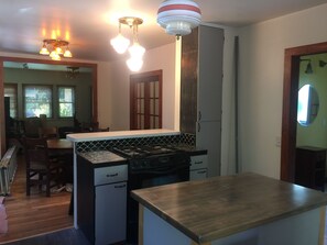 Kitchen island full of cooking items. Black downdraft duel fuel range with oven.