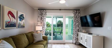 The living area has a ceiling fan and large Smart TV