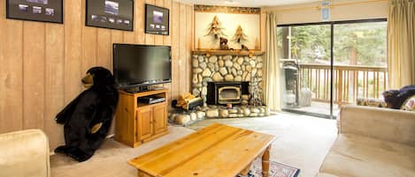 Living room with balcony access, wood burning fireplace and TV