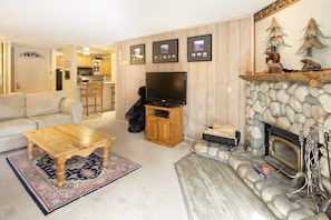 Living room with balcony access, wood burning fireplace and TV