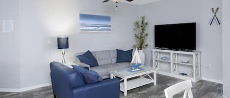 Living Room with beach themed furniture, leather couches and 65" HD Smart TV.