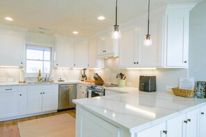Opal House features a newly renovated kitchen with white cabinets, quartz counters and stainless steel appliances.