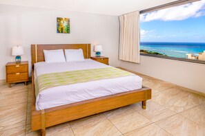 Bedroom with king-size bed, two nightstands, and ocean view.