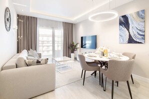 A bright living room featuring a beige sofa, soft cushions, and a coffee table, creating a comfortable space.