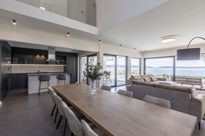 Living room with glass walls and sea/pool view