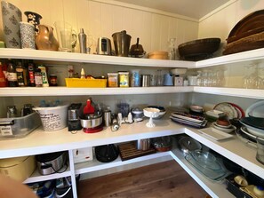 Fully equipped pantry off the kitchen, with platters, bowls and appliances