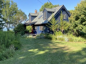 Entrance to the house over a grass lawn between flower beds.