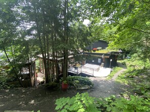 Main cottage seen from hill and parking area surrounded by brilliant green spring leaves
