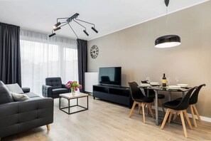 Another view of a living room, showcasing a gray sofa, decorative pillows, and a round dining table with black chairs.