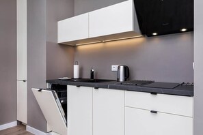 A modern kitchenette featuring white cabinets, a dining table, and pendant lighting above.