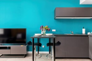 A modern kitchen with a black-and-gray color scheme. Bar stools are set along a counter for casual dining.