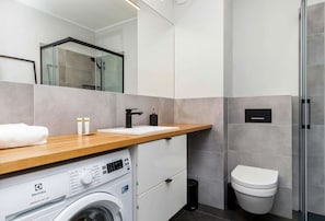 Bright bathroom with washing machine and shower cabin