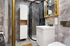 A sleek bathroom with gray and gold finishes, a mirror, and a white sink, showcasing a modern and luxurious design.