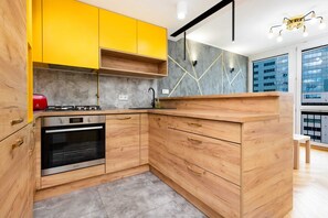 A modern kitchen with bold yellow cabinets, a wooden countertop, and gray backsplash tiles, giving the space a vibrant and contemporary look.