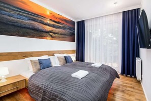 A bedroom with a double bed, navy bedding, and a large painting above the bed, creating a relaxing atmosphere.
