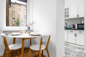 A dining table set for two near a window, surrounded by light wood chairs, creating a bright and inviting space.
