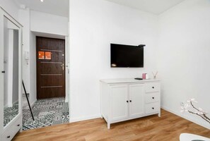 A small living area featuring a TV on a white cabinet, with a wooden floor adding warmth to the space.