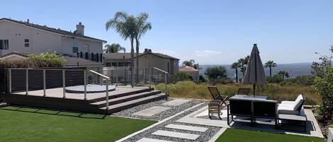 Backyard entertaining space w/deck, stock tank pool/hot tub, fire pit, and turf.