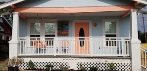 Charming beach cottage has white picket fence in front yard, porch with swing.