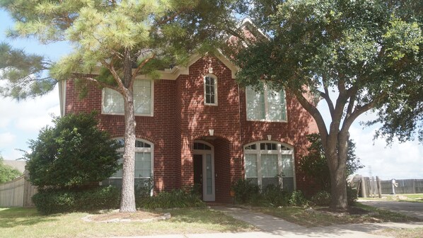 A beautiful contemporary brick house flanked by 2 mature trees.