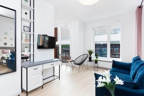 A spacious dining area combined with a living room, featuring a black dining table and chairs near large windows.
