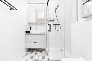 A bright bathroom with a walk-in shower, white sink, and contemporary tiles, offering a clean and fresh look.