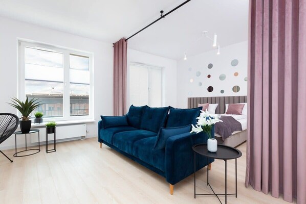 A stylish living room with a deep blue velvet sofa and modern decor elements.