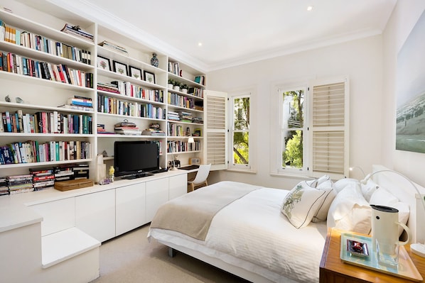 Bedroom with luxury linens and built wardrobes with six drawers.