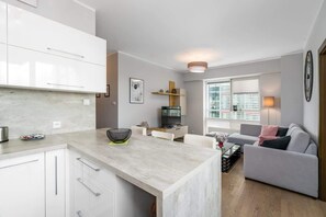 A modern white kitchen with ample counter space, built-in appliances, and under-cabinet lighting.