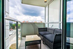 A spacious balcony with outdoor furniture, providing views of the surrounding buildings and greenery.