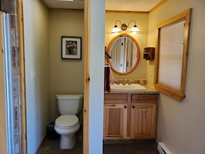 Laundry Bath Cabin has toilet with pocket door for privacy and a vanity.