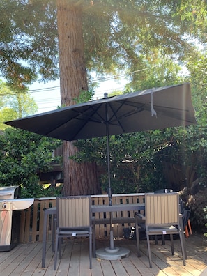 large umbrella and massive redwood trees provide cool shde