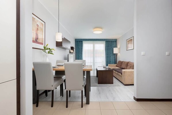 Elegant living room with dining area, sofa, coffee table, television and kitchenette.