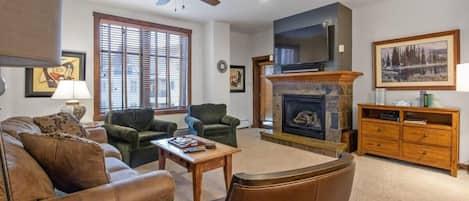 Living room with gas fireplace, mounted TV, and access to private balcony