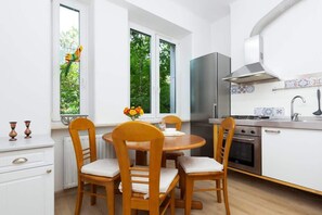 A dining area with a rustic wooden table, matching chairs, and a view of the open-plan kitchen.
