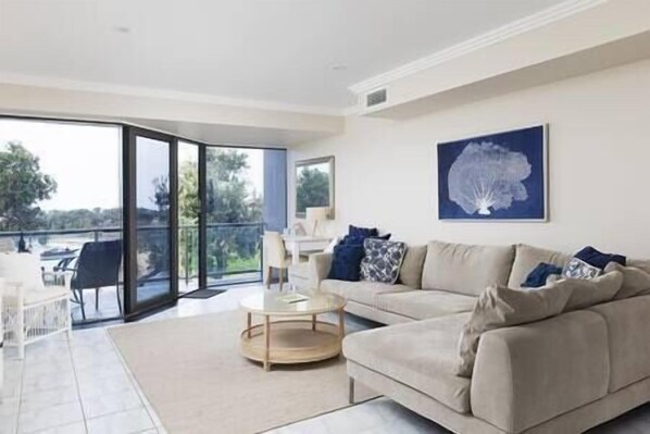 65 inch smart TV, DVD collection, desk and leads off to balcony with views across the beach and ocean.