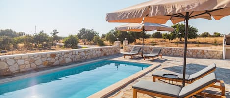 The private swimming pool with comfortable sunbeds and umbrellas.