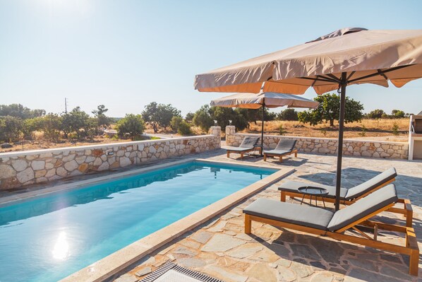 The private swimming pool with comfortable sunbeds and umbrellas.