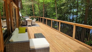 Beautiful 48x12ft deck with plush sofa as well as wooden table, chairs, and BBQ