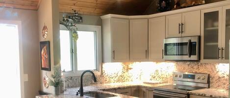 Custom designer kitchen, five stools at breakfast bar, high ceilings, chandelier