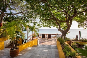 Terrace above the ocean surrounded by trees. Left side the staircase to ocean.