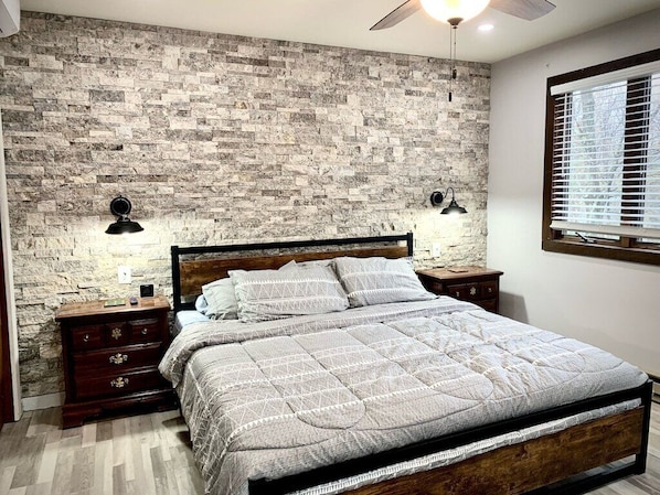 Master bedroom with real stone wall, sconce lighting, recess lighting and 65inch flat screen