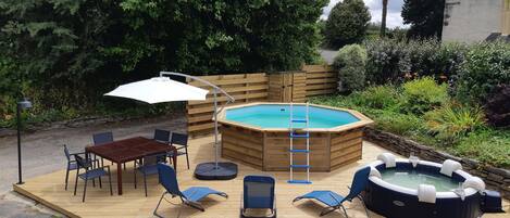 terrasse en bois avec piscine hors sol, spa, transats, tables, chaises, parasol